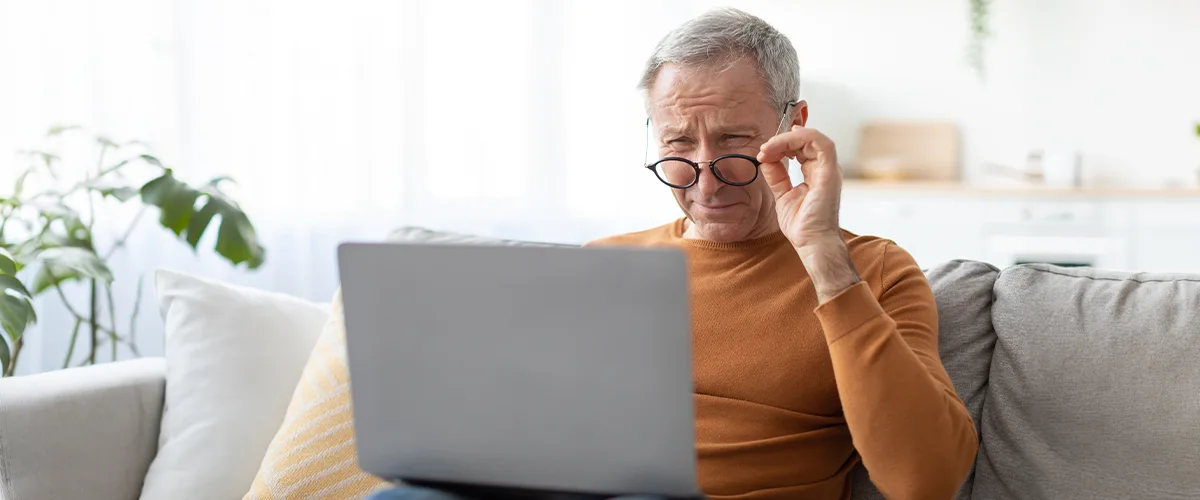 Homme de plus de 40 ans qui lit sur un ordinateur portable et remarque les premiers signes de presbytie