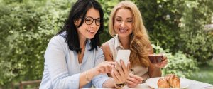 deux femmes discutant du programme récompenses d'Eye am autour d'un café et en regardant un cellulaire
