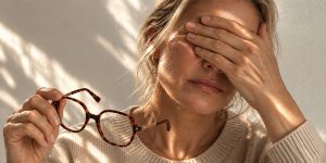Femme se frottant les yeux en tenant ses lunettes